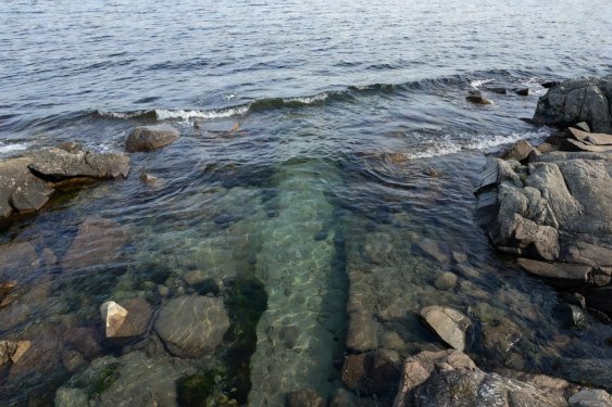 Deep clear waters of Lake Vättern breaking gently on rocky Swedish shore